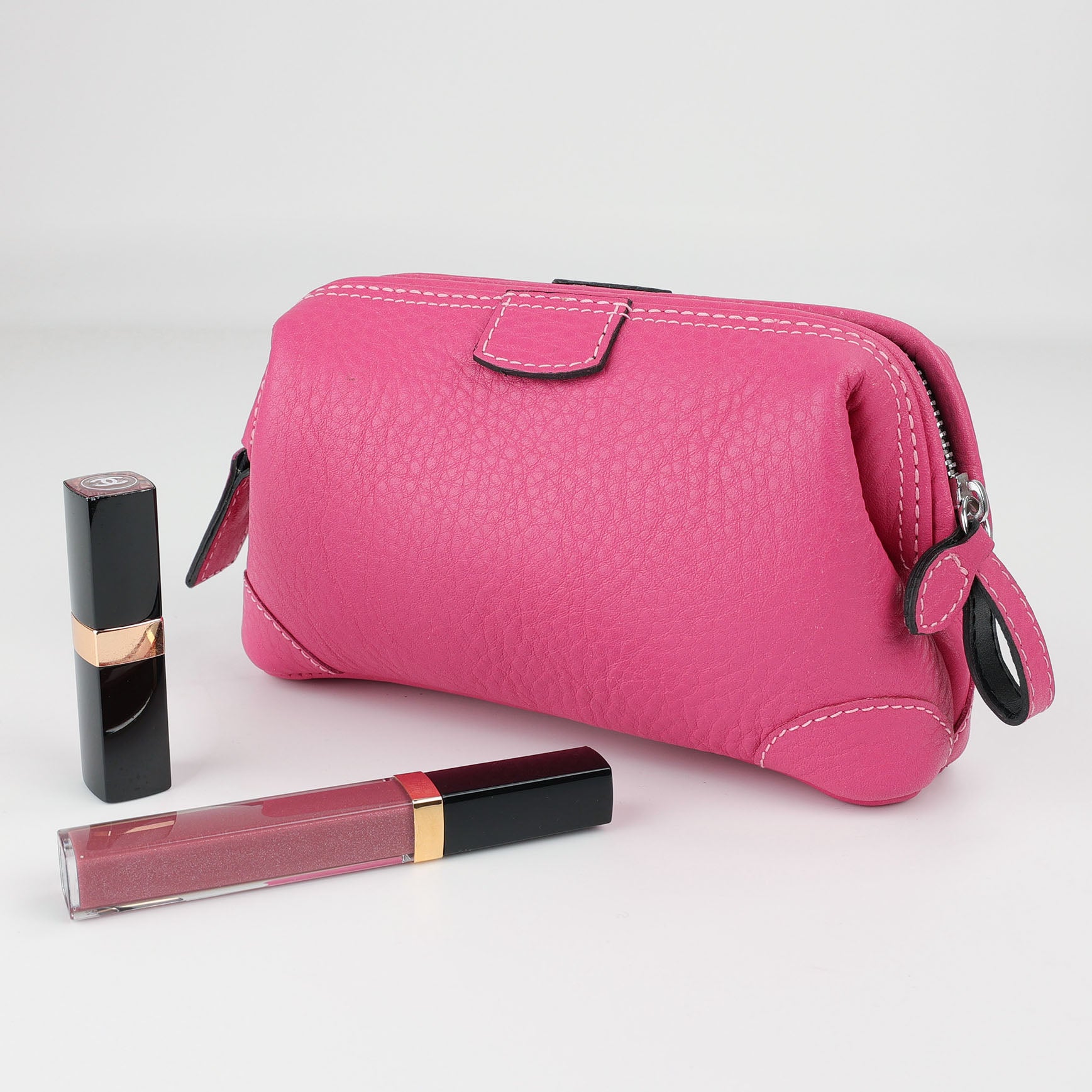 Handgefertigte Beauty Tasche aus Leder in Pink mit verdecktem Metallbügel, dazu Lipgloss und Lippenstift